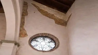 Grandes superficies de pared desprendidas, se ve el ladrillo en al interior de la iglesia.