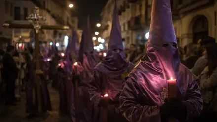 Nazarenos de "La O", con su vistosa túnica morada en raso junto a la cruz de guía en la noche.