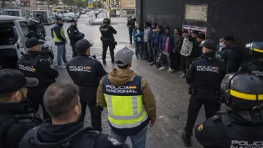 Muchos policías vigilando a un grupo de personas sospechosas.
