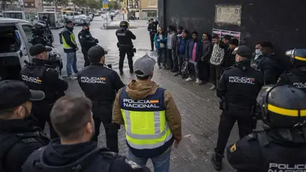 Muchos policías vigilando a un grupo de personas sospechosas.