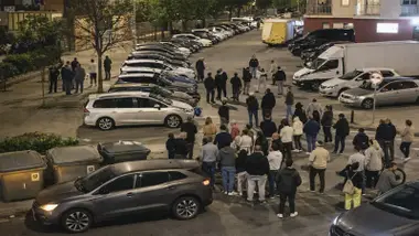 Muchos vecinos en una calle con coches en busca de gorrillas.
