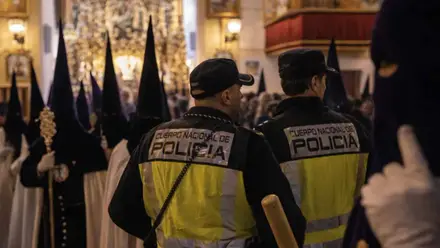 Dos agentes de la Policía entre nazarenos de la Madrugá de Sevilla.