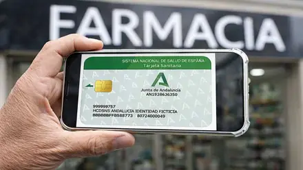 Mano sosteniendo un móvil con la tarjeta sanitaria.