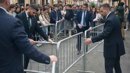 Varios hombres de chaqueta colocan unas vallas.