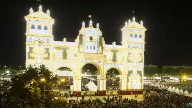 Noche del alumbrado de la Feria de Sevilla con la portada iluminada.