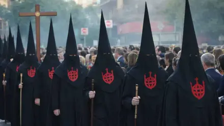 Fila de nazarenos del Santo Entierro con túnica negra y escudo rojo.