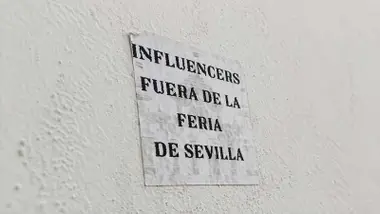 Cartel pegado en una pared donde se puede leer: "Influencers fuera de la Feria de Sevilla".