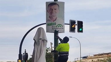 Operario desmontando un cartel electoral.
