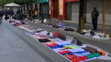 Manteros colocados en la calle San Jacinto de Triana con ropa y bolsos.
