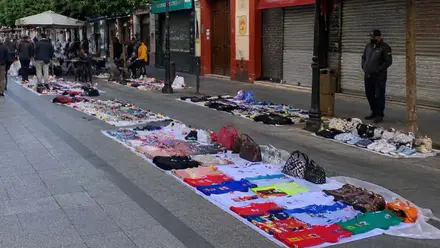 Manteros colocados en la calle San Jacinto de Triana con ropa y bolsos.
