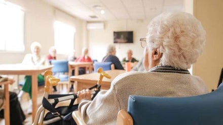 Centro de mayores con ancianos. Jay una señora en silla de ruedas de espalda.
