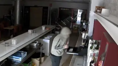 Ladrón con sudadera gris y capucha en pleno robo.