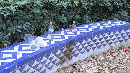 Banco de azulejo con botellas de whisky y basura.