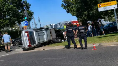 Coche volcado en color plateado con agentes de la Policía Nacional cerca del mismo.