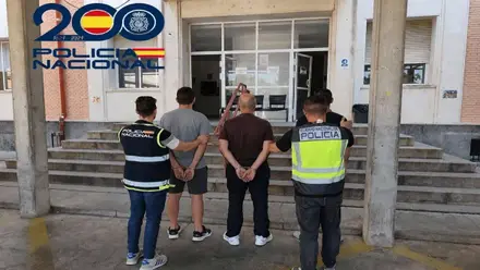 Policías llevan a unos detenidos a la comisaría.