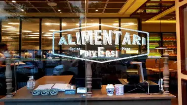 Escaparate con el nombre del restaurante italiano Alimentari en Sevilla.