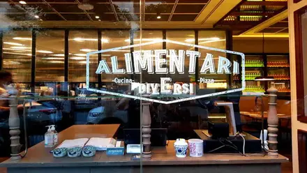 Escaparate con el nombre del restaurante italiano Alimentari en Sevilla.