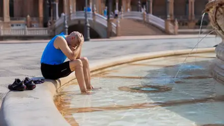 Hombre mete los pies en una fuente de la Plaza de España ante la sofocante calor.