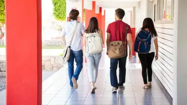 Cuatro alumnos de bachillerato por un pasillo de su centro.