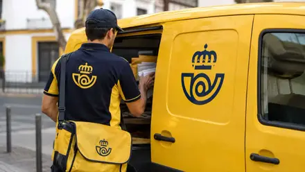 Trabajador de Correos con su furgoneta amarilla.