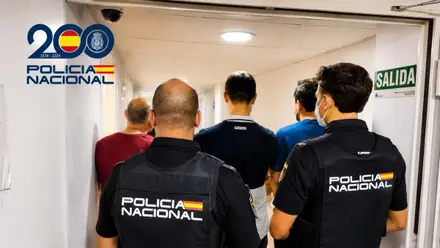 Dos policías nacionales conduciendo a unos detenidos a las instalaciones de comisaría.
