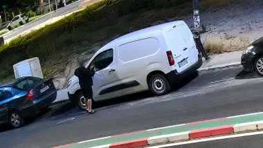 Furgoneta blanca que está siendo robada por un hombre que viste ropa negra veraniega.