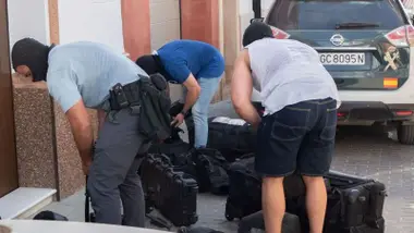 Policías con la cara cubiertas transportando el material de la intervención.