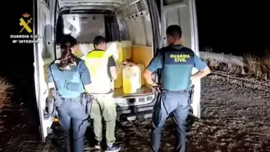 Dos agentes de la Guardia Civil junto al conductor de una furgoneta cargada de bidones de gasolina.